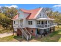 Charming two-story home with a red roof, complemented by lush surroundings at 1214 Tabby Dr, Folly Beach, SC 29439