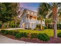 Inviting two-story home with lush lawn, mature palm trees, and a welcoming front porch with classic white railing and facade at 1212 Clonmel Pl, Mount Pleasant, SC 29464