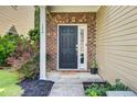 Inviting front door with brick surround, adjacent to the covered porch and manicured landscaping at 134 Longford Dr, Summerville, SC 29483