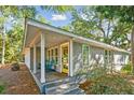 Charming coastal home featuring a shake shingle exterior, inviting front porch, and lovely mature landscaping at 248 Forest Trail, Isle of Palms, SC 29451