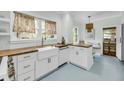 Modern kitchen features white cabinets, butcher block counters, farmhouse sink and bright blue floors at 27 Stocker Dr, Charleston, SC 29407