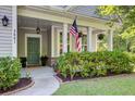 Inviting front porch with American flag, decorative lanterns, and neatly trimmed shrubs at 3001 Grand Bay Ln, Johns Island, SC 29455