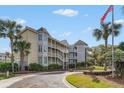 Low country condominium building, palm trees, and the American flag on a sunny day at 9000 Palmetto Dr # 202-C, Isle of Palms, SC 29451