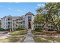 Condominium building featuring multiple stories and private balconies with lush landscaping and walkway at 9000 Palmetto Dr # 202-C, Isle of Palms, SC 29451