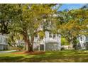 Charming white two-story home with double porches and lush landscaping, nestled under mature trees at 1409 Lieben Rd, Mount Pleasant, SC 29466