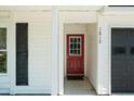 Close-up of the red front door, flanked by white siding and black shutters, for a pop of color at 1812 Overrun St, Charleston, SC 29414