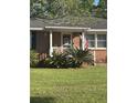 Attractive brick home featuring a manicured lawn, a cozy porch, and decorative plantings, creating a welcoming entrance at 210 Ellen St, Goose Creek, SC 29445