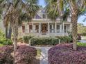 Beautiful Southern-style home with a welcoming porch, manicured landscaping, and mature palm trees framing the entryway at 2104 Royal Pine Dr, Seabrook Island, SC 29455