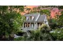 A charming two-story home with inviting porch, dormer windows, and lush landscaping set against a vibrant sky at 2104 Royal Pine Dr, Seabrook Island, SC 29455