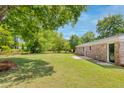 Expansive backyard with lush green lawn, mature trees, and a brick exterior creating a private outdoor space at 4432 Logwood Drive, Ladson, SC 29456