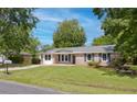 Traditional brick home featuring classic shutters and a lush front lawn with mature trees on a sunny day at 4432 Logwood Drive, Ladson, SC 29456