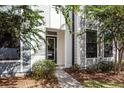 Close up of the front door with sidelight windows, light gray siding and decorative trees at 4577 Summey St, North Charleston, SC 29405