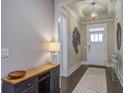 Inviting foyer with stylish light fixture, elegant decor, and a view of the front door and hardwood floors at 5049 Song Sparrow Way, Summerville, SC 29483