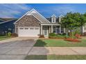 Charming home featuring stone accents, a two-car garage, manicured lawn, and a neatly landscaped front yard at 5049 Song Sparrow Way, Summerville, SC 29483