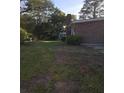 Grassy backyard with mature landscaping and partial view of the side of the brick house at 5937 Willard Dr, Hanahan, SC 29410