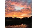 Vibrant sunset of fiery orange and red skies over a serene marsh, with reflections in the water at 642 Harbor Creek Pl # 21, Charleston, SC 29412
