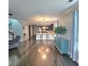 Spacious living room with hardwood floors flowing into kitchen area featuring modern lighting and appliances at 7406 Purser Ln, Hanahan, SC 29410
