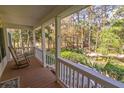 Covered back porch with beautiful wooded backyard views and a wooden rocking chair at 8551 Pope Landing Rd, Edisto Island, SC 29438