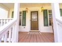 Inviting front porch with a decorative glass front door and green shutters at 8551 Pope Landing Rd, Edisto Island, SC 29438