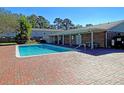 Community pool surrounded by a brick patio and lush greenery at 415 Parkdale Dr # 12D, Charleston, SC 29414