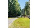 A gravel driveway leads to a charming rural property, framed by lush trees and greenery at 6935 Hickorynut Ln, Ravenel, SC 29470