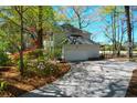 A view of the home's garage, side yard with flowering bushes, and basketball hoop at 12 Trail Hollow Ct, Charleston, SC 29414