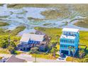 Stunning aerial view of a coastal property showcasing its location near marsh, other beautiful homes, and nearby road at 1604 E Ashley Ave, Folly Beach, SC 29439