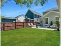 A spacious backyard featuring a lush green lawn, privacy fence, and outdoor lounge area at 1673 Emmets Rd, Johns Island, SC 29455