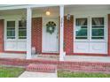 Close-up of charming brick front porch with decorative wreath, plants, and ample natural light at 201 Judith Dr, Summerville, SC 29485