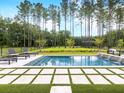 A stunning backyard pool surrounded by lush green grass and stone tiles is perfect for relaxation at 208 Quimby Hill Dr, Huger, SC 29450