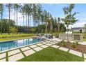 A luxurious backyard oasis featuring a pool, built-in grill, outdoor seating and lush landscaping at 208 Quimby Hill Dr, Huger, SC 29450