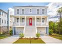 Stunning two-story home with a red front door, white railings, and a two-car garage at 3107 S Shore Dr, Charleston, SC 29407