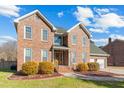 Beautiful two-story brick home featuring a manicured lawn, mature bushes, and an attached two-car garage at 406 King Charles Cir, Summerville, SC 29485