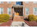 Elegant front entrance featuring a stylish wooden door, brick steps, and meticulously maintained landscaping at 406 King Charles Cir, Summerville, SC 29485