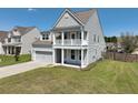 Inviting two-story home with a double porch, garage and manicured lawn on a sunny day at 514 Morelets Dr, Moncks Corner, SC 29461