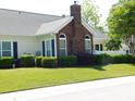 Backyard view showing brick chimney, green grass and mature shrubbery around the home at 8800 Dorchester Rd # 2902, North Charleston, SC 29420