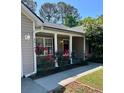 Inviting covered front porch with blooming flower bushes and classic architectural details at 9914 Levenshall Dr, Ladson, SC 29456