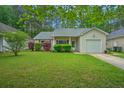 Charming one-story home with a well-manicured lawn, mature trees, and an attached garage at 1016 Providence Way, Summerville, SC 29483