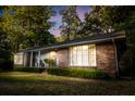 Classic brick home with mature trees, tidy landscaping, and welcoming front porch with picture window at 114 California Ave, Moncks Corner, SC 29461