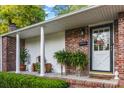 Charming front porch features brick accents, ferns, and a stylish front door with glass and decorative wreath at 114 California Ave, Moncks Corner, SC 29461