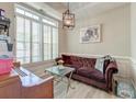 Inviting sitting room with a stylish chandelier, large window with shutters, and comfortable plum colored couch at 208 Evesham Dr, Summerville, SC 29485