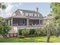 Rear exterior elevation featuring a screened porch with seating and a lush green lawn at 2407 Atlantic Ave, Sullivans Island, SC 29482