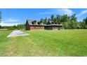 Sprawling log home on a lush green lawn with a long driveway and mature trees at 3936 Lodge Hwy, Smoaks, SC 29481