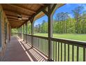 Covered porch with wooden flooring and railings, offering scenic views of the surrounding greenery at 3936 Lodge Hwy, Smoaks, SC 29481