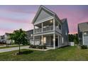 Charming two-story home with a welcoming front porch and well-maintained lawn at dusk at 427 W Respite Ln, Summerville, SC 29483
