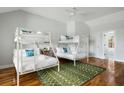 Bright bedroom with two sets of white bunkbeds, hardwood floors, a ceiling fan, and a decorative green rug at 4979 Lake Palmetto, North Charleston, SC 29418