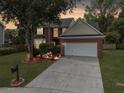 Charming two-story brick home with illuminated landscaping and a spacious driveway at twilight at 5403 Diston Ct, North Charleston, SC 29420