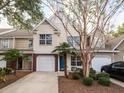 Townhome exterior featuring attached garage, palm trees, brick accents, and concrete driveway at 8679 Grassy Oak Trl, North Charleston, SC 29420
