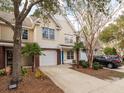 Townhome exterior featuring attached garage, palm trees, brick accents, and concrete driveway at 8679 Grassy Oak Trl, North Charleston, SC 29420