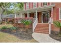 Inviting front porch with brick steps, white railings, and lush landscaping enhancing curb appeal at 8781 Laurel Grove Ln, North Charleston, SC 29420